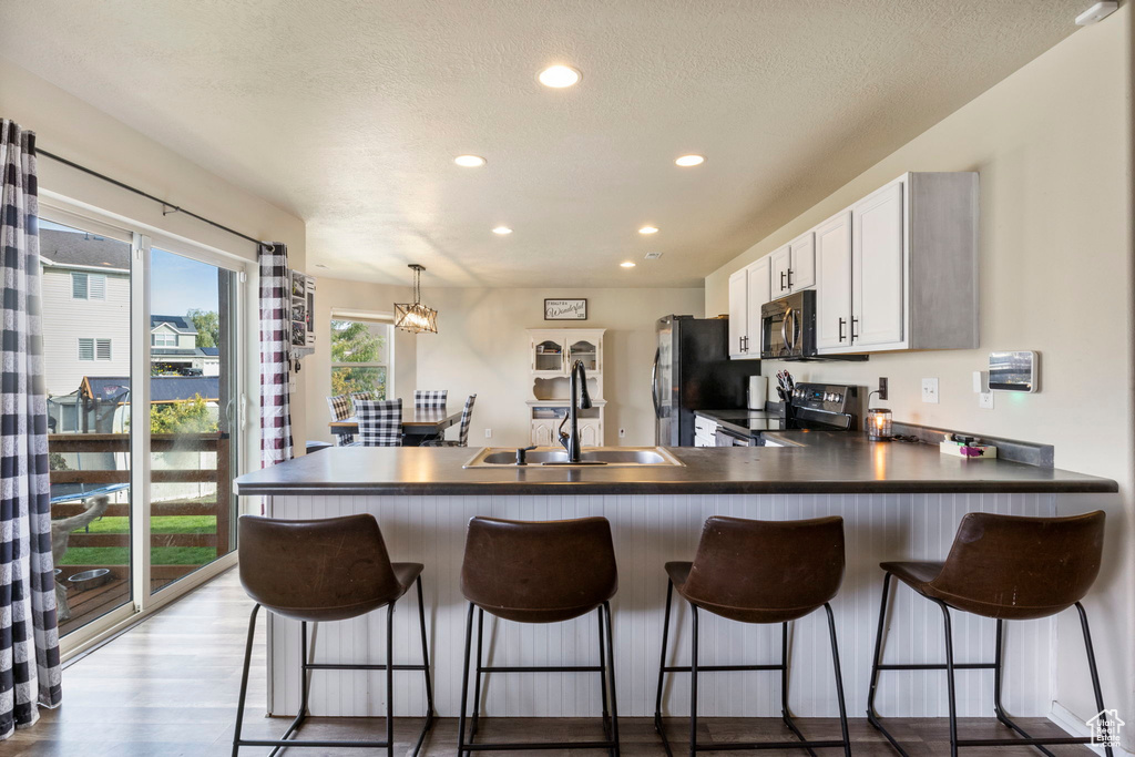 Kitchen with dark countertops, stainless steel electric stove, freestanding refrigerator, and a sink