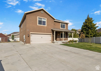 Traditional home with stucco siding, a front lawn, fence, covered porch, and an attached garage