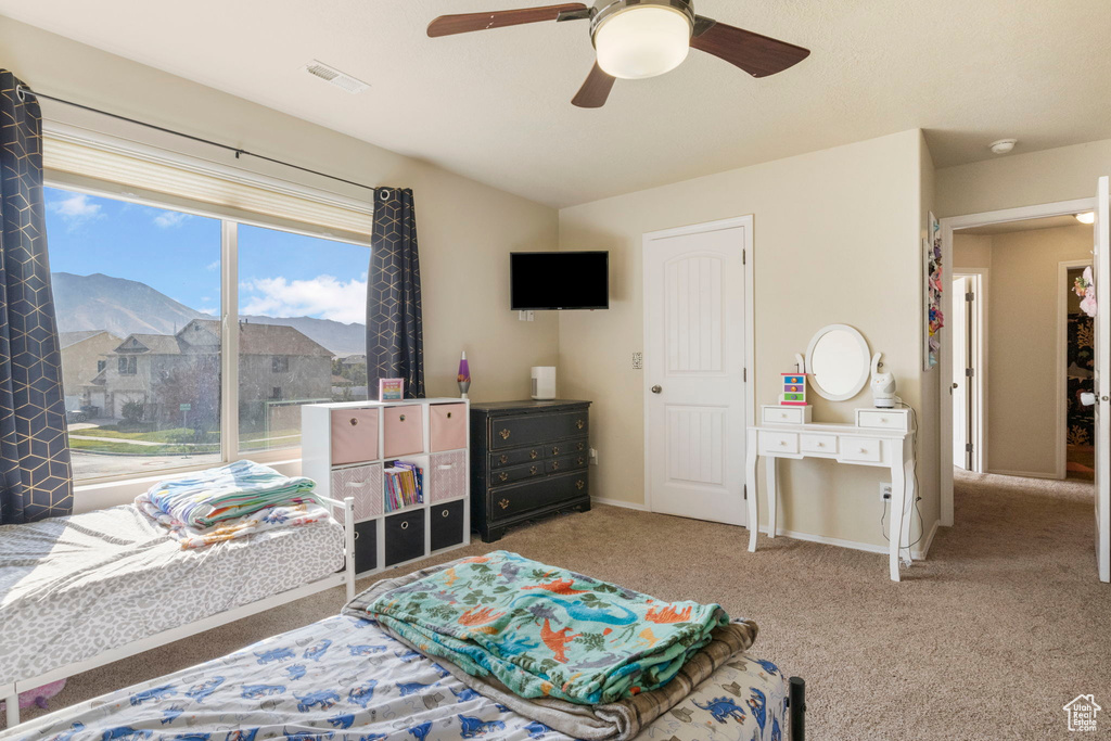 Carpeted bedroom with visible vents, a mountain view, a ceiling fan, and baseboards