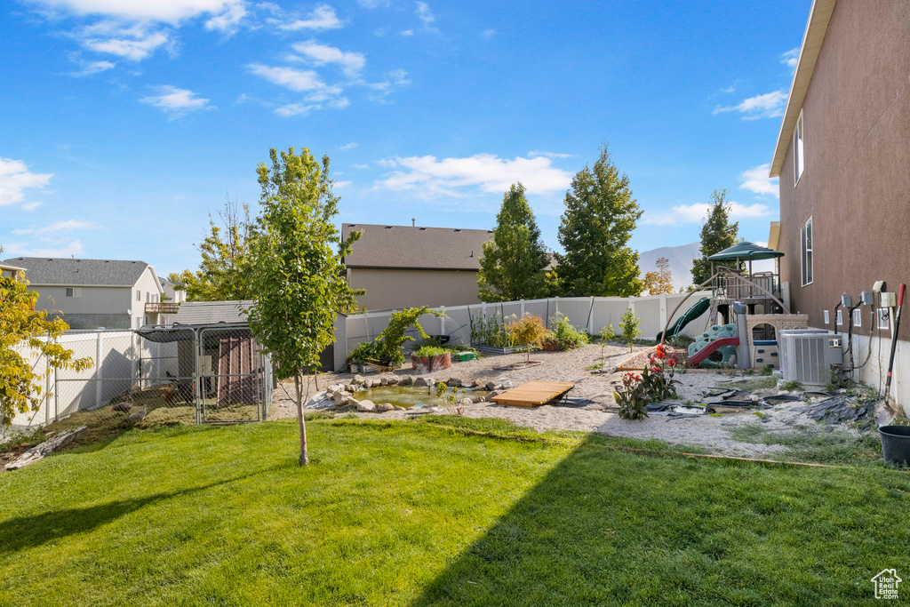 View of yard with a playground, cooling unit, and a fenced backyard