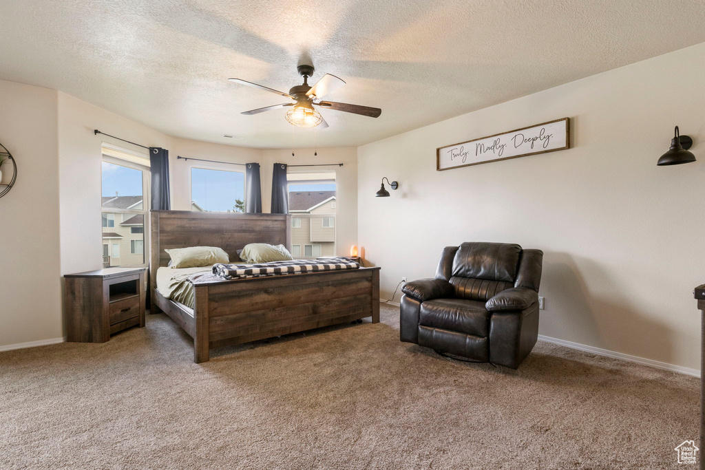 Carpeted bedroom with a ceiling fan, baseboards, and a textured ceiling