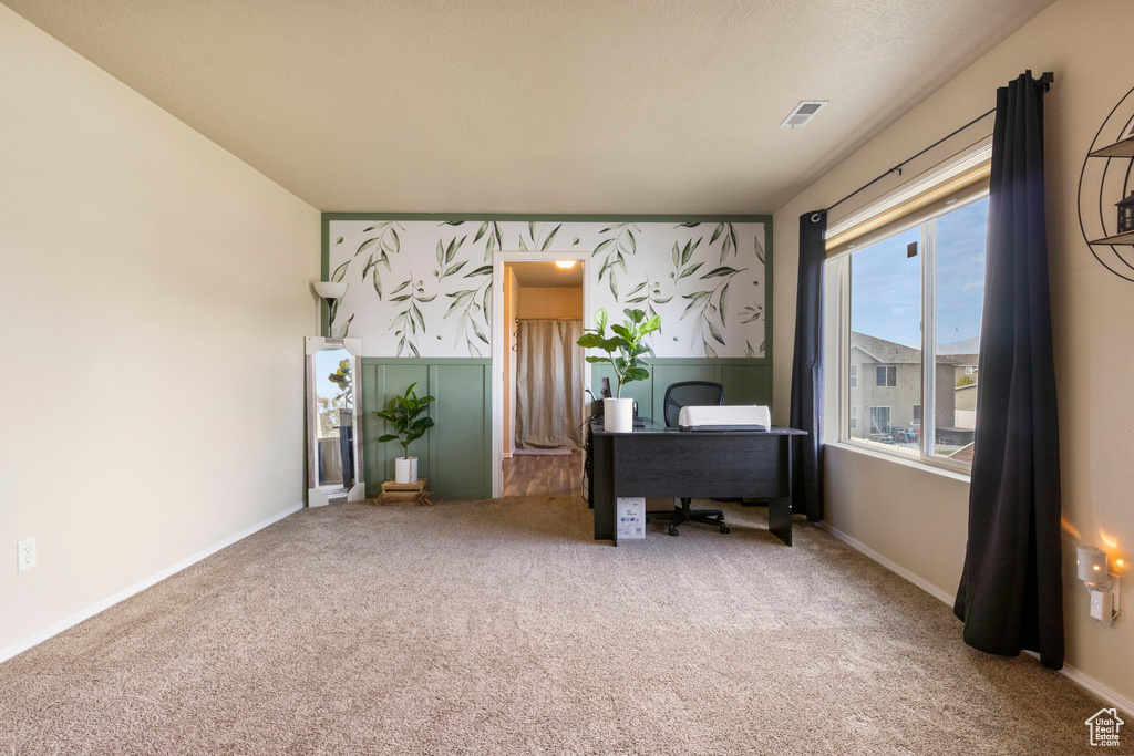 Carpeted home office with visible vents and baseboards