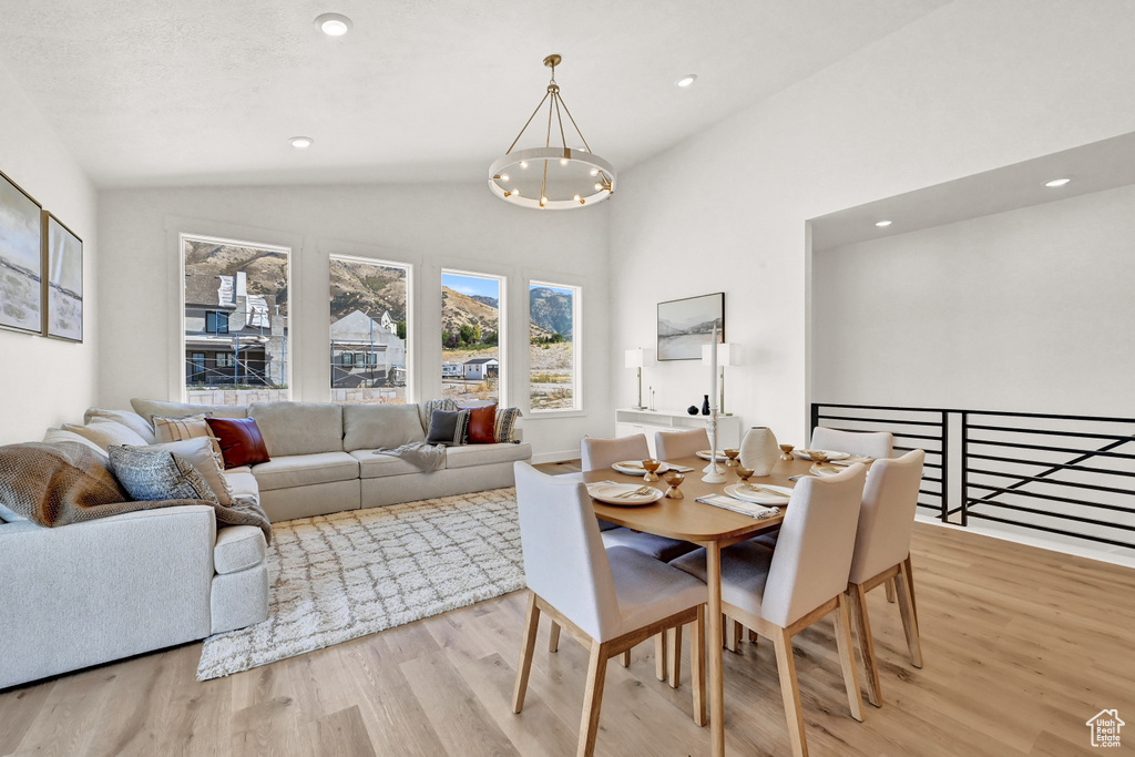 Dining room featuring light wood finished floors, a notable chandelier, recessed lighting, and vaulted ceiling