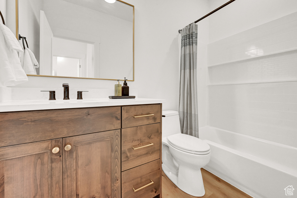 Bathroom featuring shower / tub combo, toilet, wood finished floors, and vanity