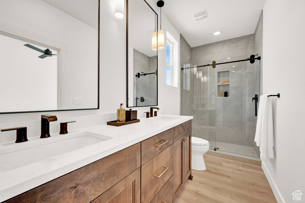 Bathroom with double vanity, wood finished floors, a stall shower, and a sink