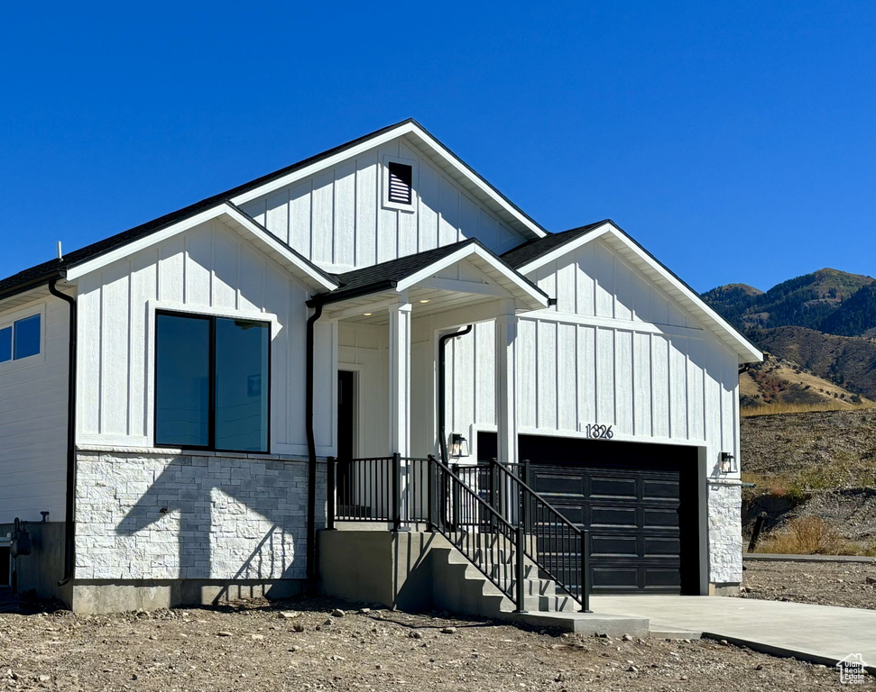 View of front of house featuring a mountain view, a garage, board and batten siding, and stone siding