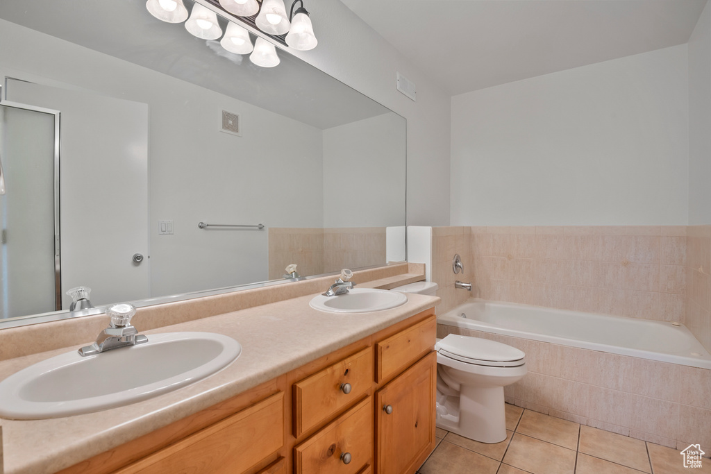 Full bath featuring tile patterned flooring, a garden tub, double vanity, and toilet