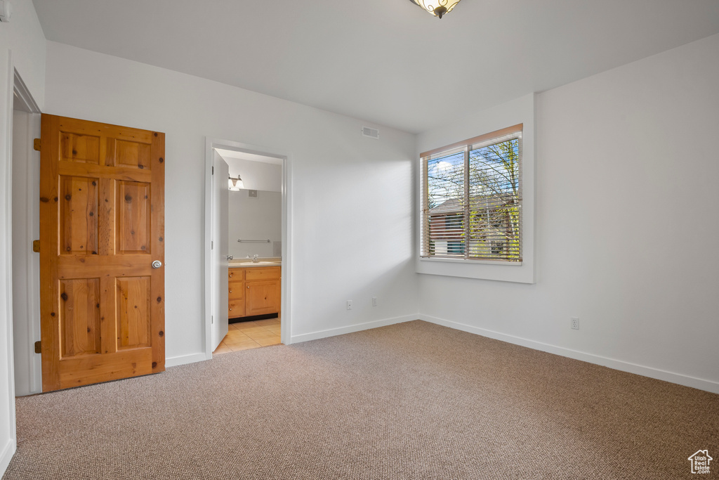Unfurnished bedroom featuring light carpet, a sink, baseboards, and connected bathroom