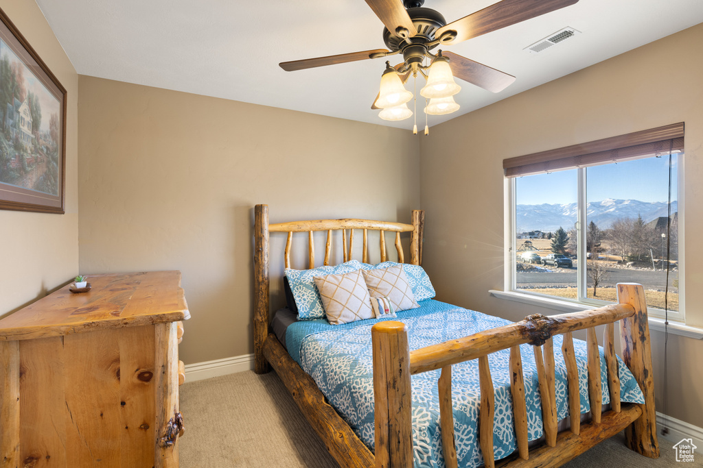 Carpeted bedroom featuring visible vents, ceiling fan, a mountain view, and baseboards