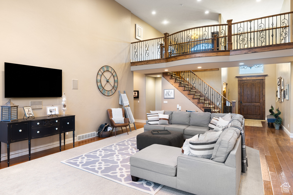 Living area with visible vents, baseboards, stairs, a towering ceiling, and wood finished floors