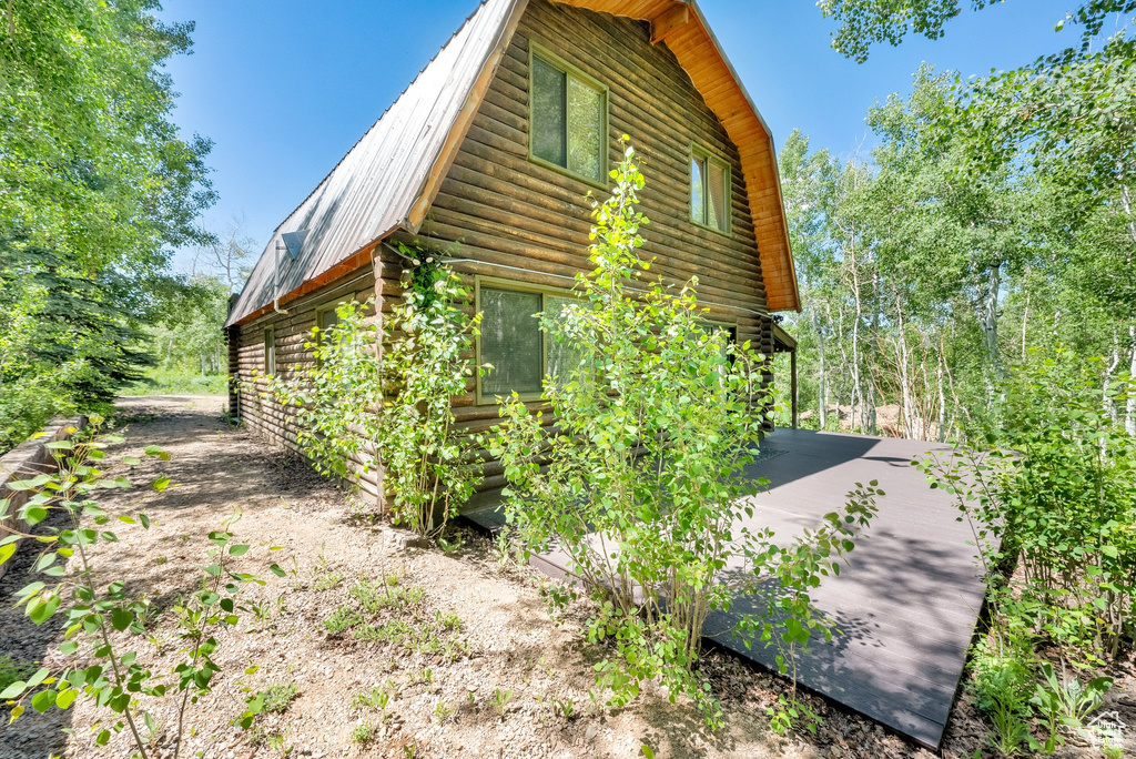 View of property exterior with log siding, a gambrel roof, and metal roof