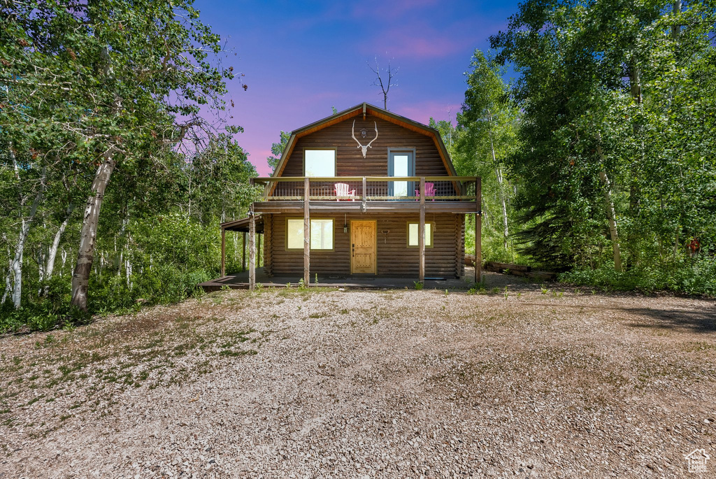 Back of property at dusk featuring a gambrel roof