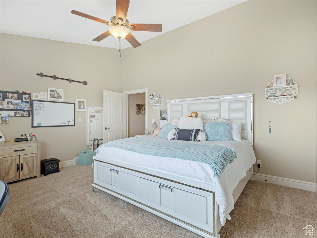 Bedroom with light carpet, ceiling fan, baseboards, and vaulted ceiling