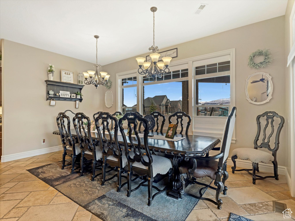 Dining room featuring visible vents, baseboards, an inviting chandelier, and stone tile floors