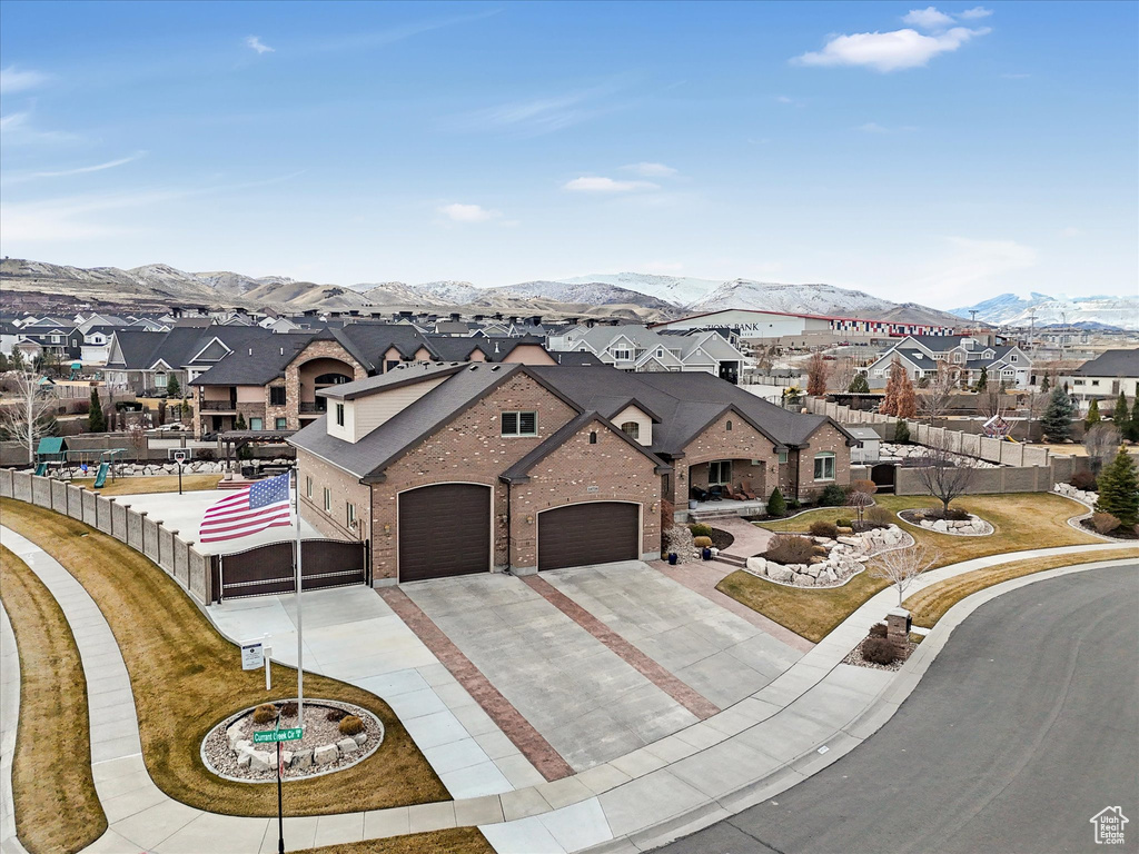 View of front of house with a mountain view, a residential view, driveway, and fence