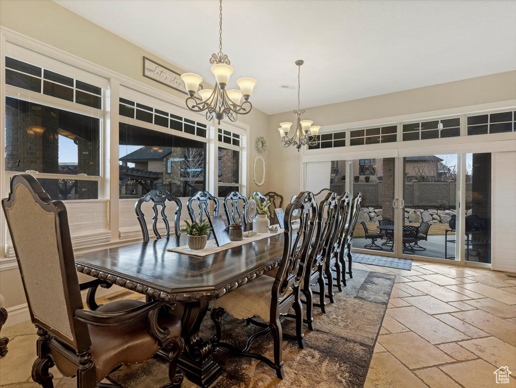 Dining space with a chandelier and stone tile floors