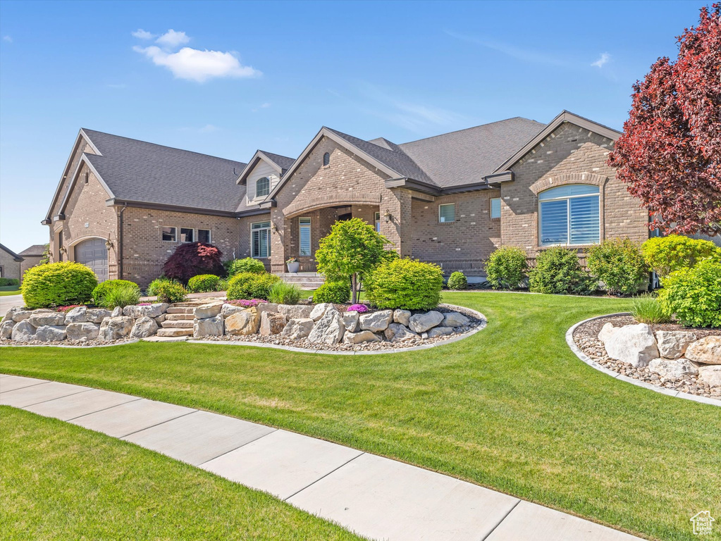 View of front of home featuring brick siding, a front yard, and a shingled roof