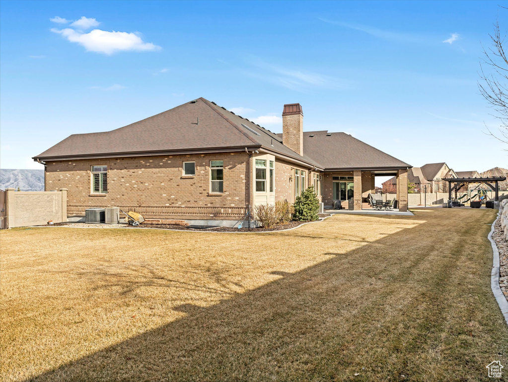 Rear view of property with a patio, fence, a chimney, central air condition unit, and brick siding