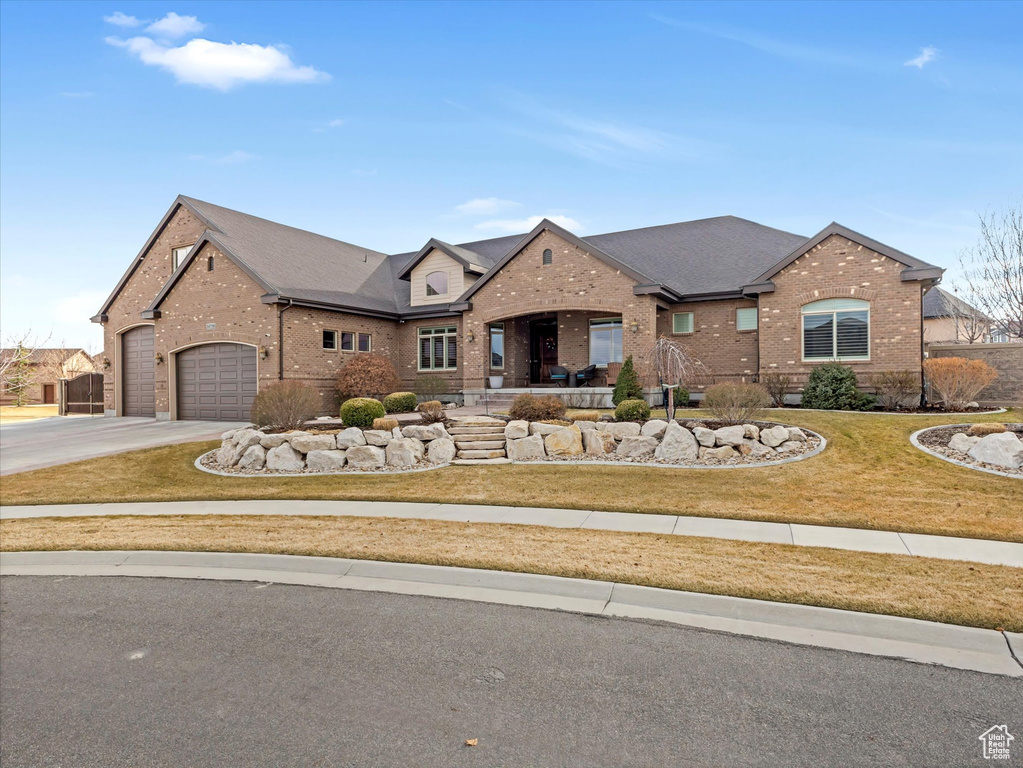 View of front facade featuring brick siding, a garage, concrete driveway, and a front yard