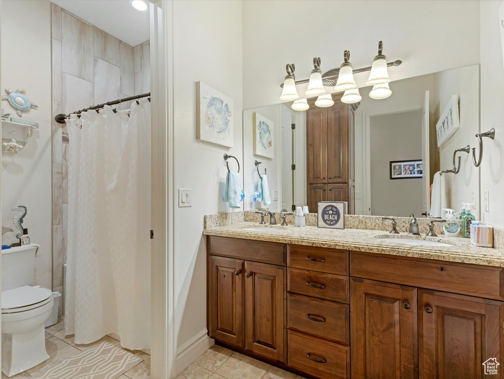 Full bath featuring tile patterned flooring, double vanity, toilet, and a sink