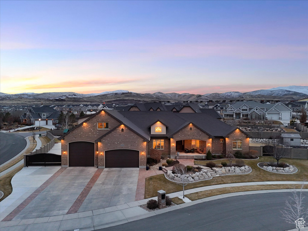 View of front of property featuring a mountain view, a residential view, concrete driveway, a garage, and brick siding