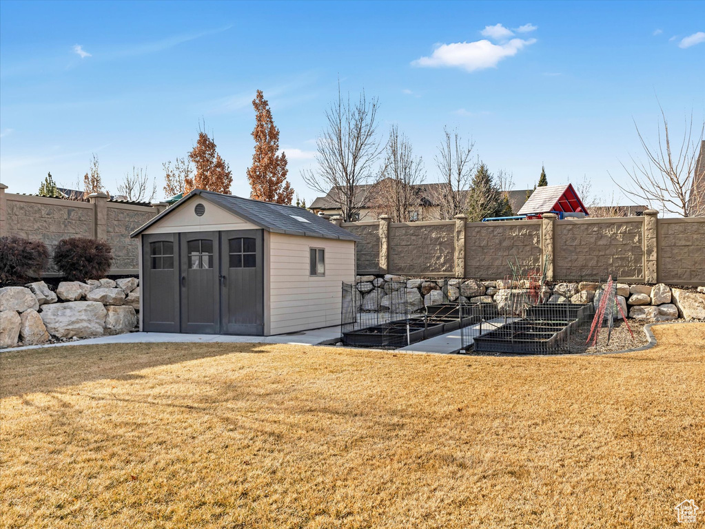 View of yard with a fenced backyard, a storage unit, and an outdoor structure