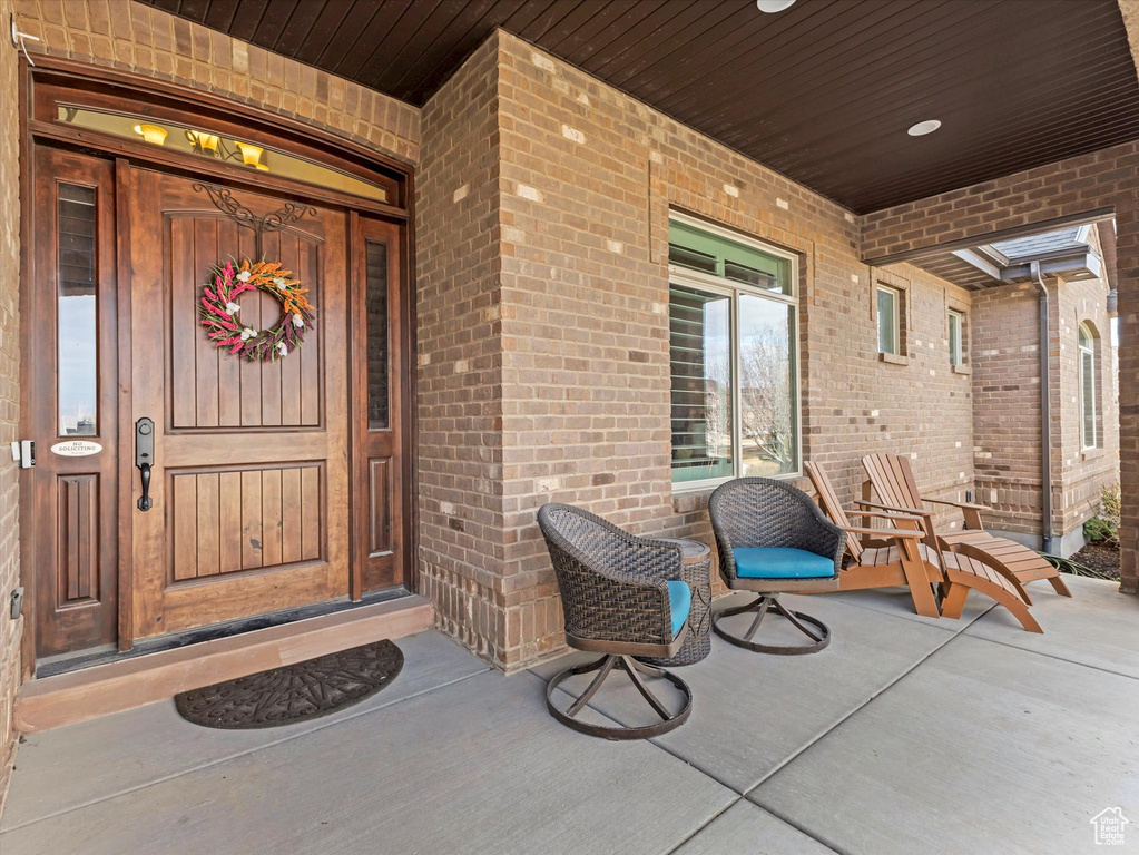 Entrance to property with a porch and brick siding