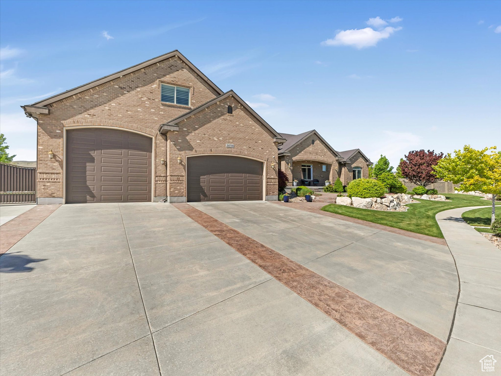 View of front facade with brick siding, driveway, and a garage