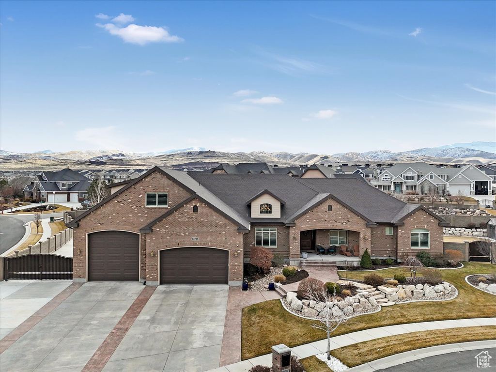 View of front of property with a mountain view, a residential view, brick siding, and concrete driveway