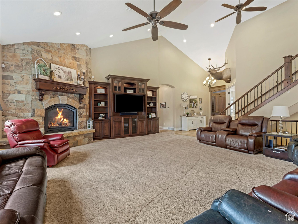 Living area featuring stairs, ceiling fan with notable chandelier, a fireplace, arched walkways, and high vaulted ceiling