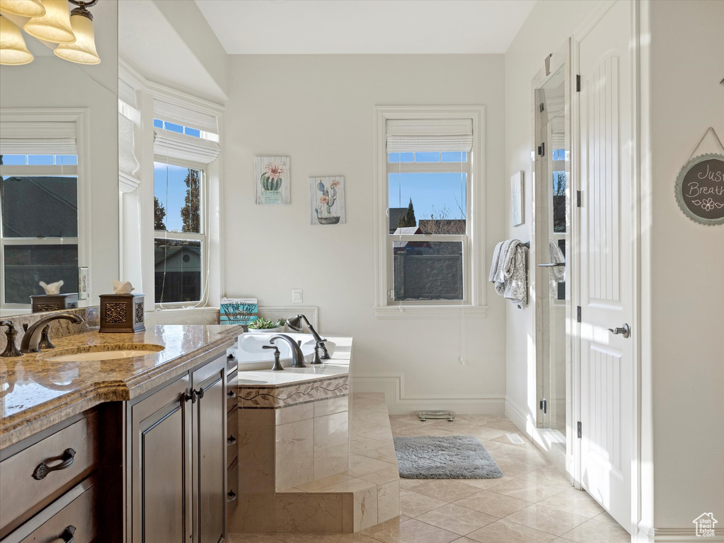 Bathroom with vanity, a garden tub, baseboards, and tile patterned flooring