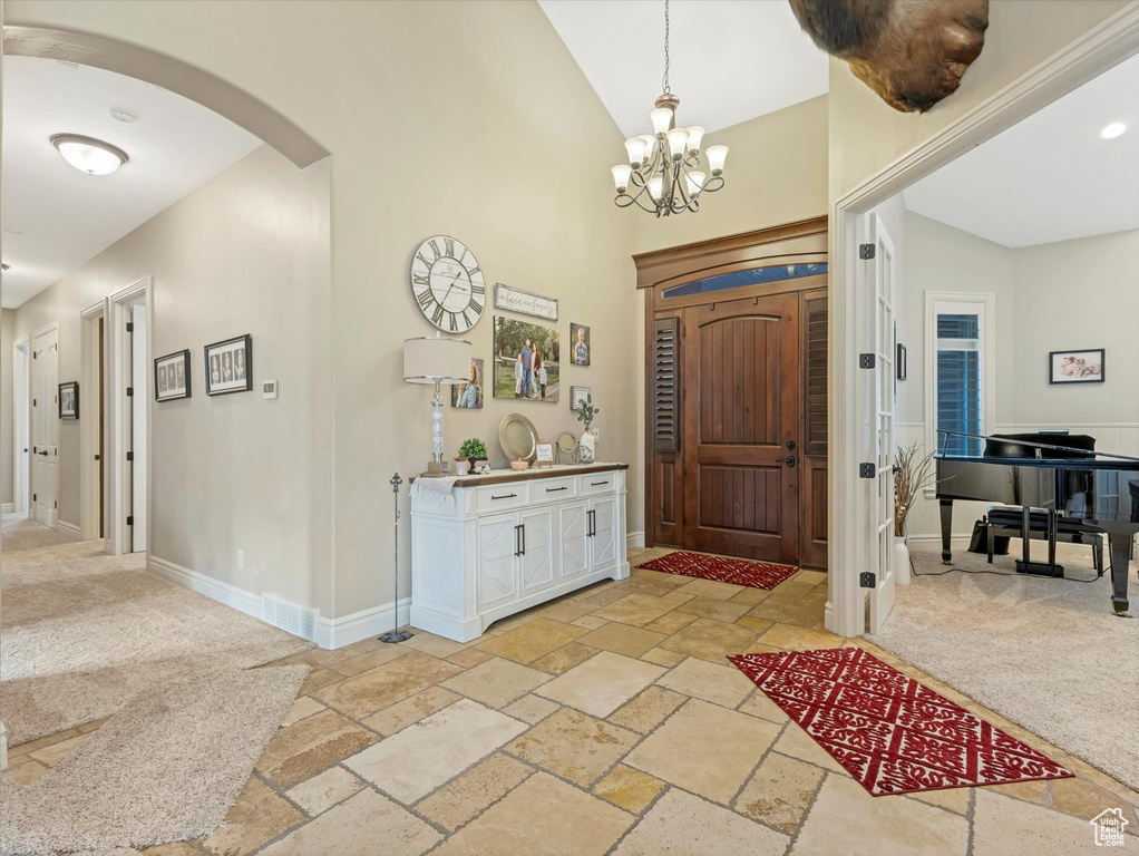 Entrance foyer with stone tile floors, light colored carpet, arched walkways, and baseboards