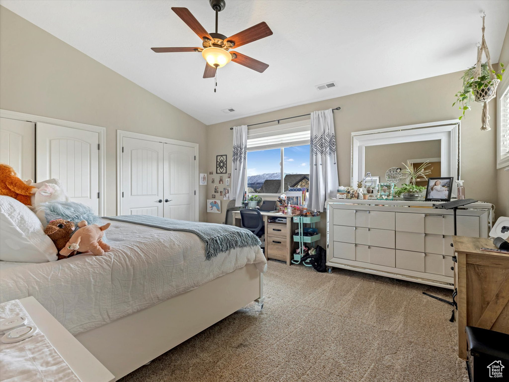 Bedroom featuring a ceiling fan, visible vents, vaulted ceiling, carpet flooring, and two closets