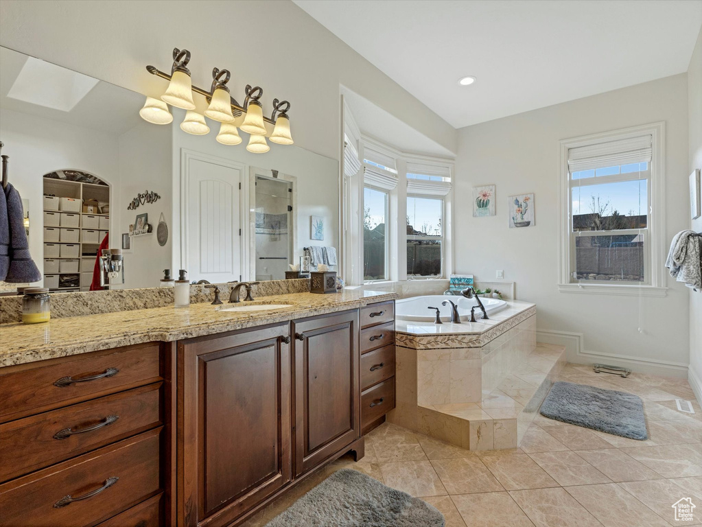 Full bathroom with a wealth of natural light, tile patterned flooring, vanity, and a garden tub