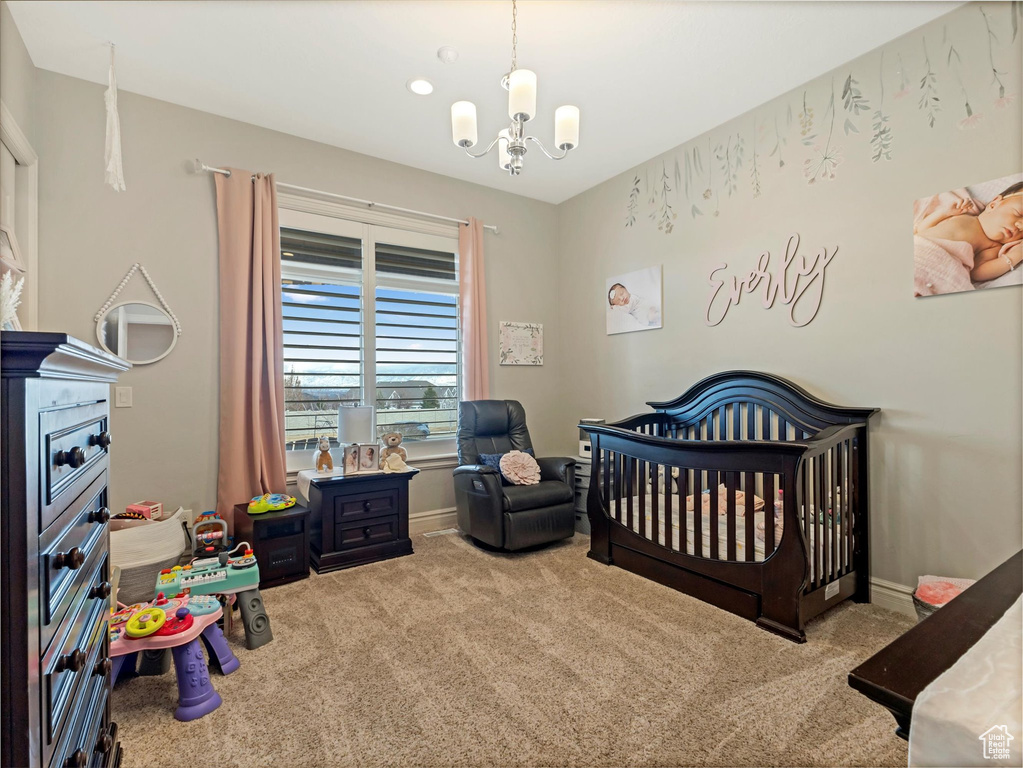 Bedroom with baseboards, carpet floors, a nursery area, and an inviting chandelier