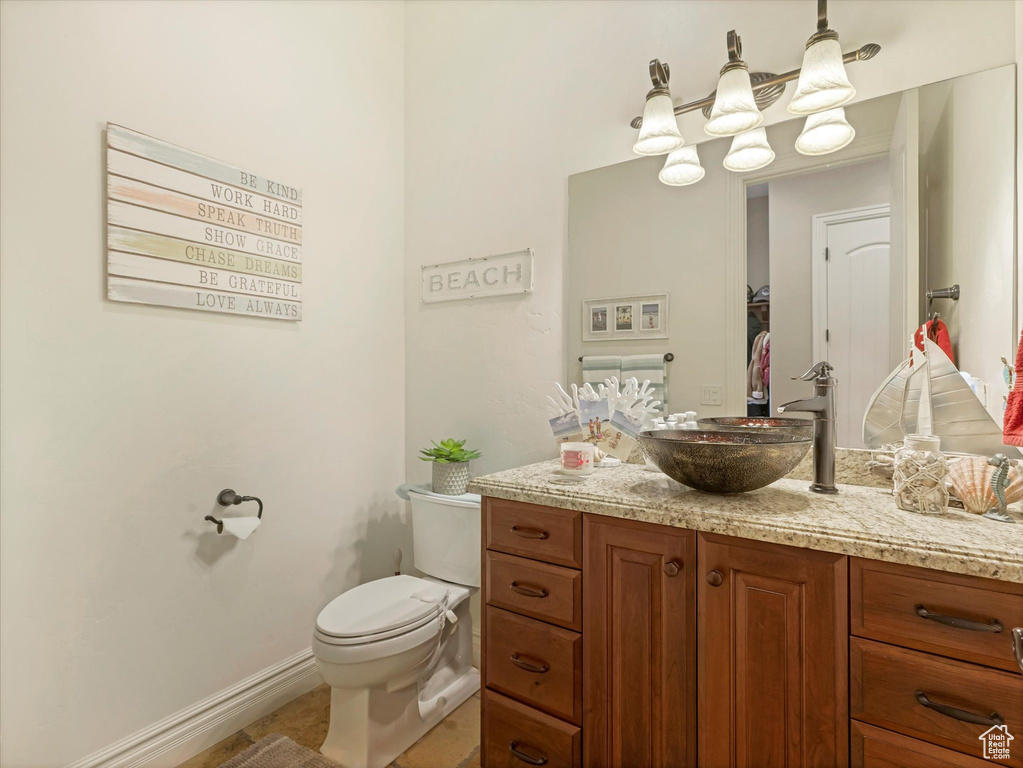 Half bathroom with tile patterned floors, toilet, vanity, and baseboards