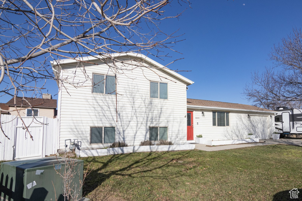 Rear view of house featuring a yard and fence