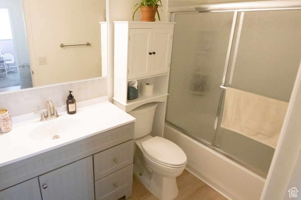 Bathroom featuring vanity, toilet, and enclosed tub / shower combo