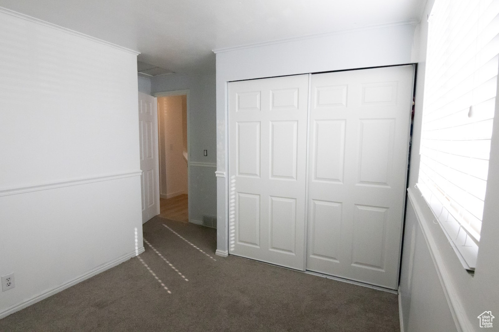 Unfurnished bedroom featuring crown molding, carpet flooring, and a closet