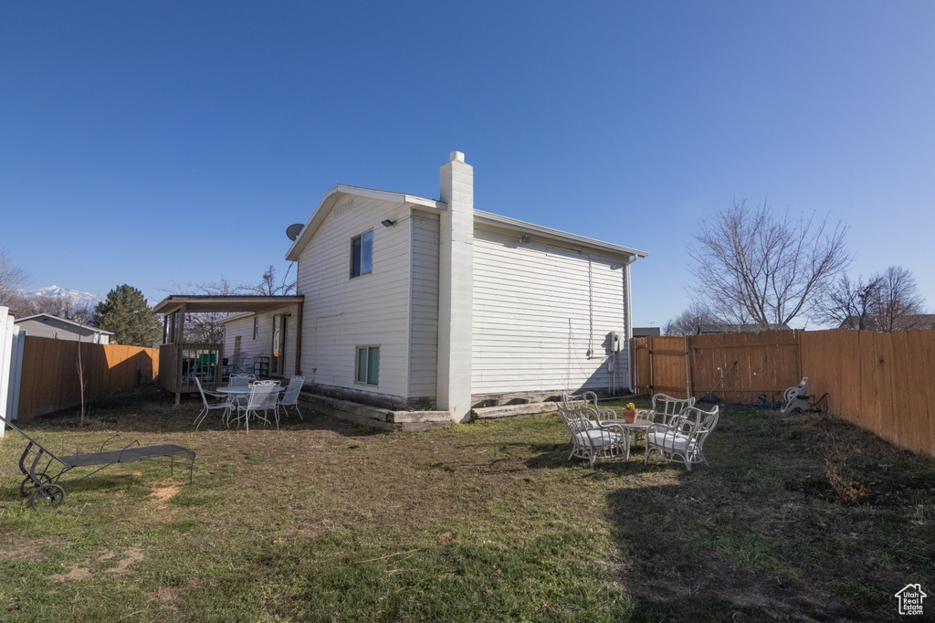 Back of property with a yard, a fenced backyard, and a chimney