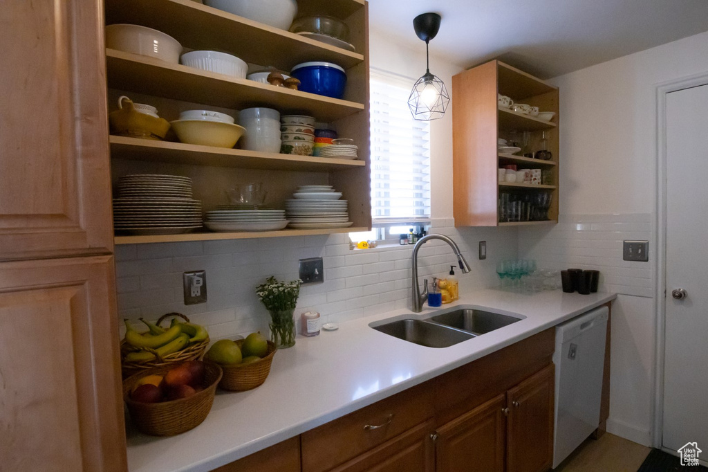 Kitchen featuring a sink, backsplash, dishwasher, light countertops, and open shelves