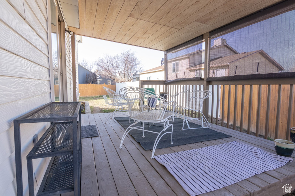 Wooden terrace featuring outdoor dining space and fence