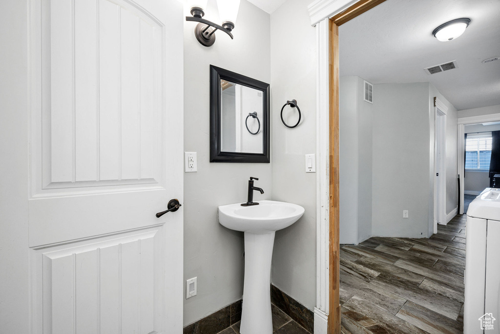 Bathroom with a sink, visible vents, washer / dryer, and wood finished floors