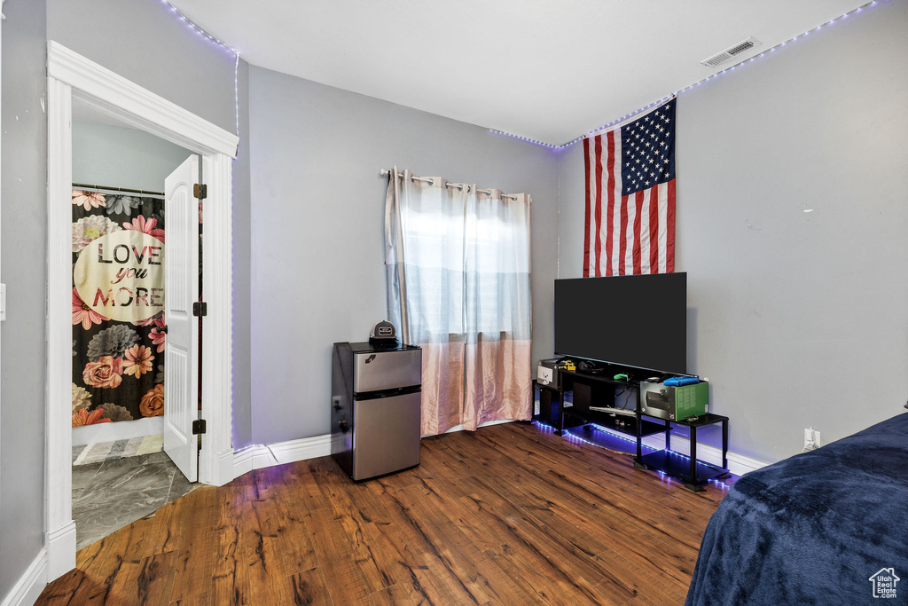 Bedroom with visible vents, freestanding refrigerator, baseboards, and wood finished floors