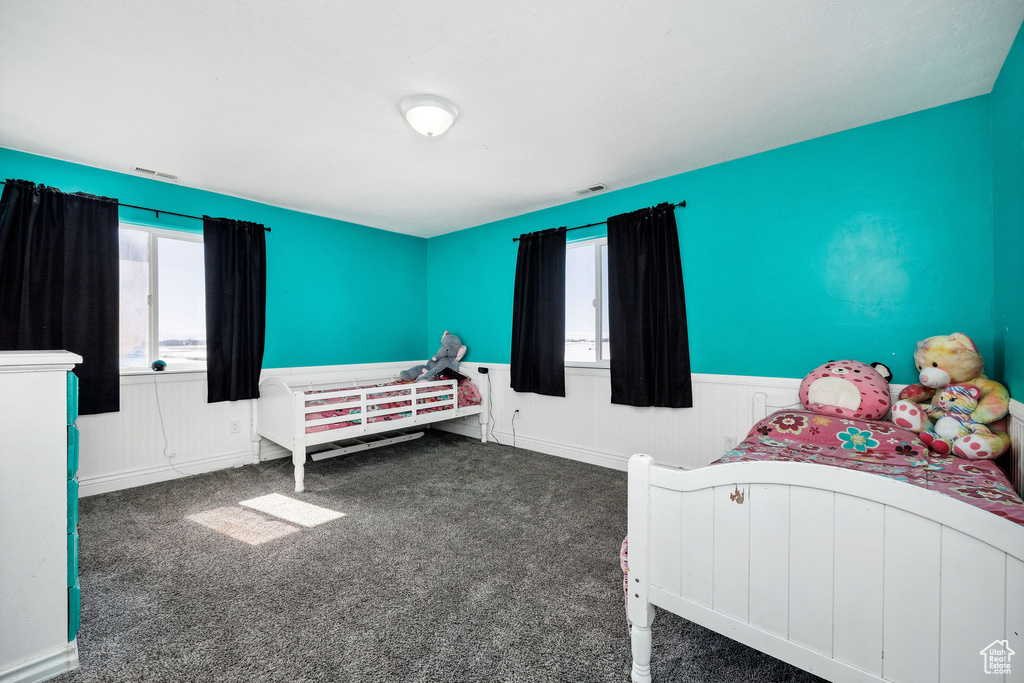 Bedroom with wainscoting, visible vents, multiple windows, and carpet flooring