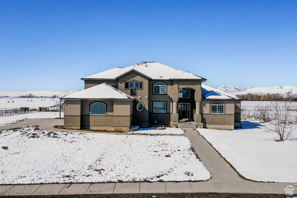 View of front of property with stucco siding, a mountain view, and fence