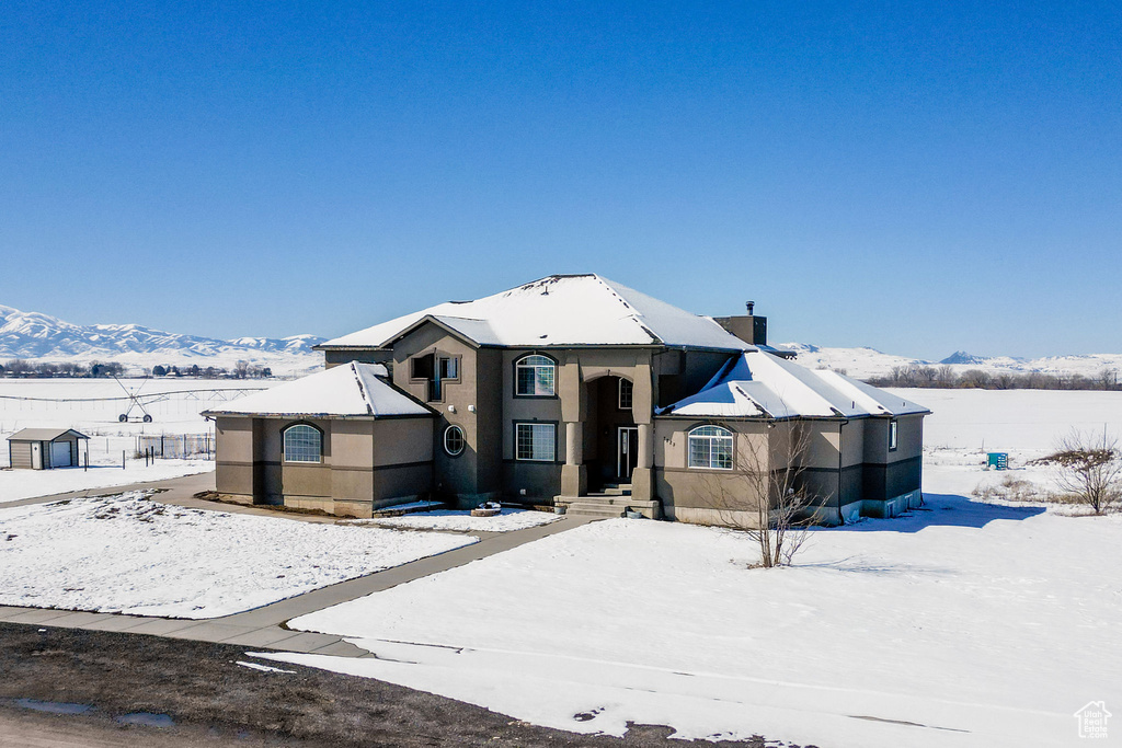 View of front of home featuring stucco siding, a mountain view, and a chimney