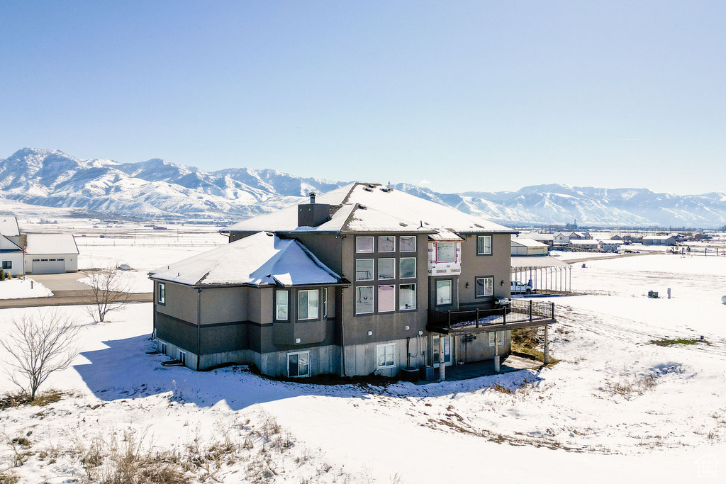 Snow covered rear of property with a mountain view and a chimney