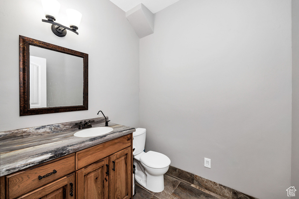 Half bathroom featuring baseboards, toilet, and vanity