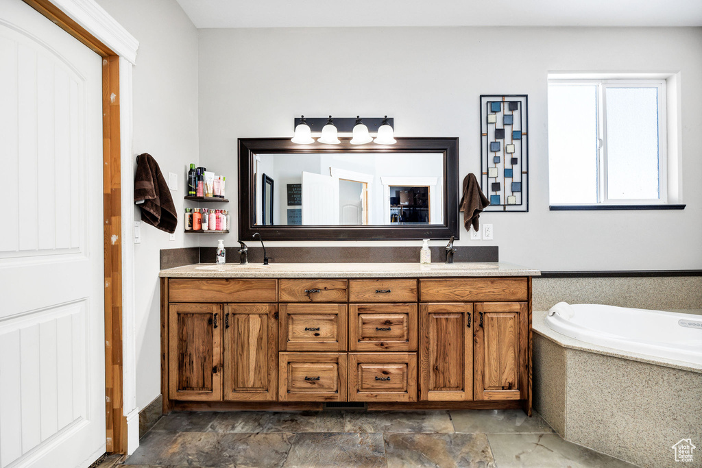 Full bath featuring a sink, a garden tub, and double vanity